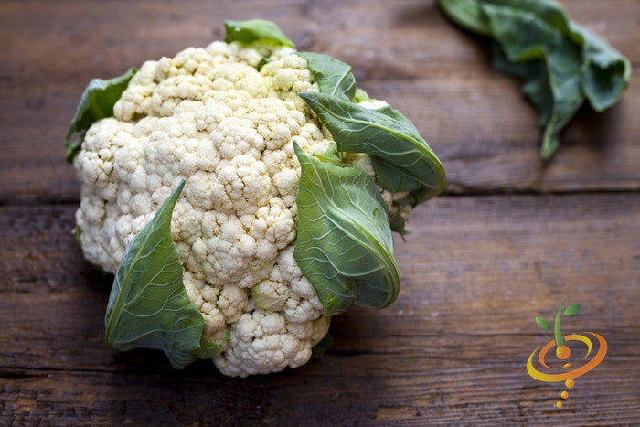 Fresh white cauliflower head with green leaves on wooden surface for all year round seeds