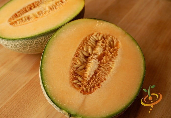 Honey Rock cantaloupe melon cut in half showing orange flesh and seeds on wooden surface