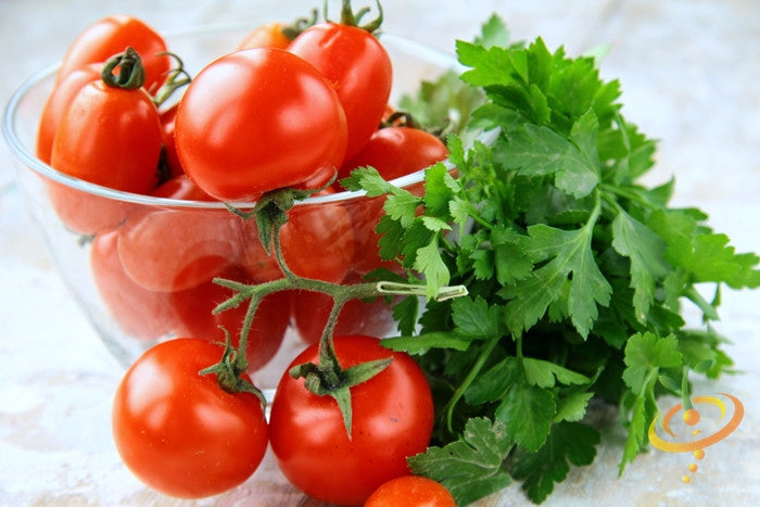Bright red tomatoes in a glass bowl next to fresh Dark Green Italian Giant parsley leaves